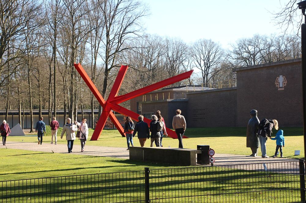 Bezoekers bij een rood beeld in de beeldentuin van het Kröller-Müller Museum
